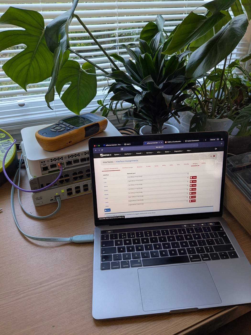 pfSense interface configuration on a laptop next to network hardware