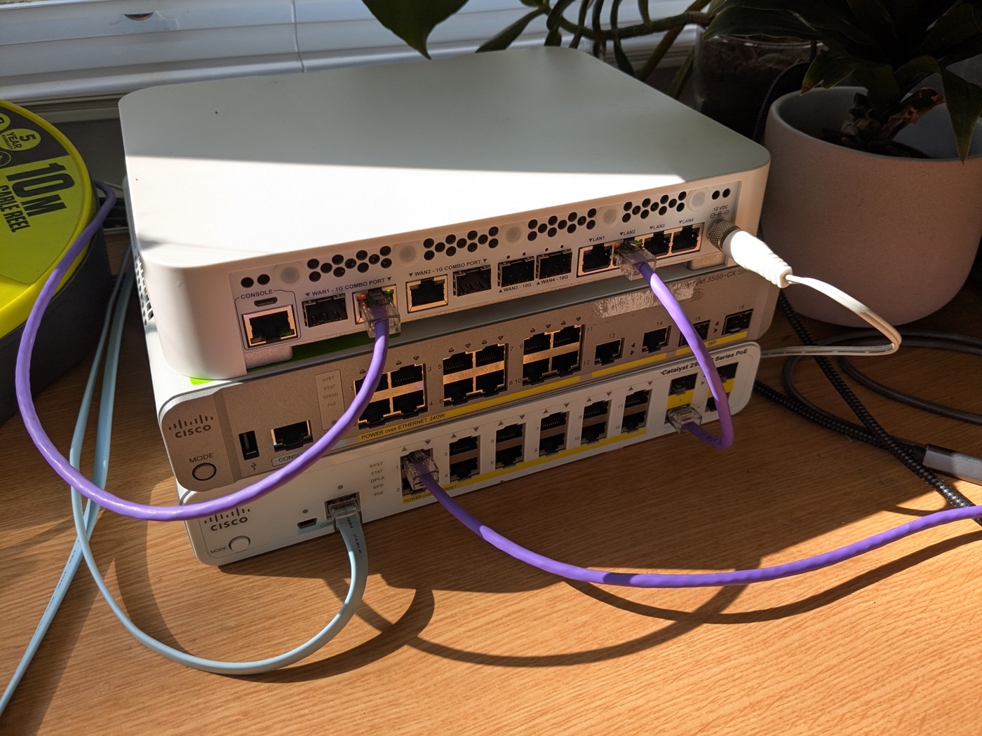 Stacked Cisco switches and router with patch leads on a desk
