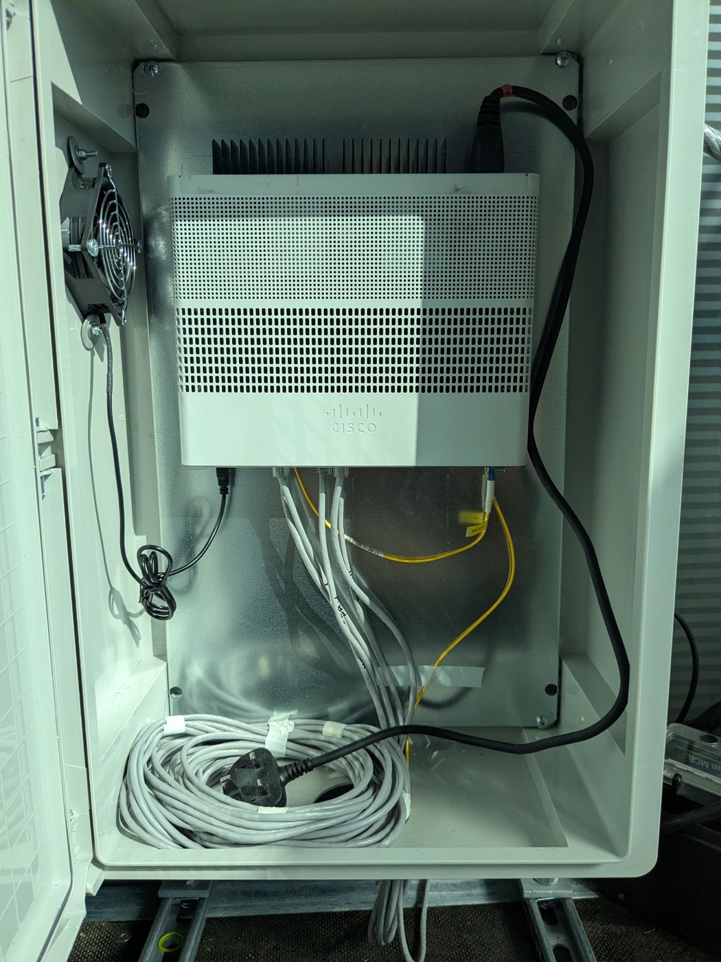 Cisco router installed in a weatherproof outdoor cabinet with cooling fan